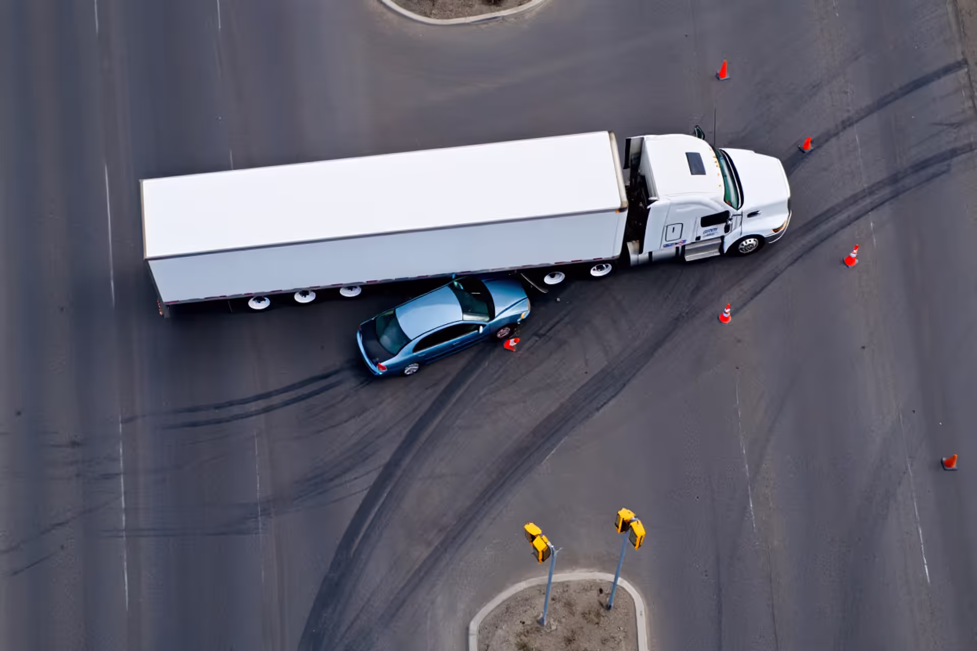 Aerial view of a semi-truck collision with a passenger car at an intersection showing the massive size difference between vehicles